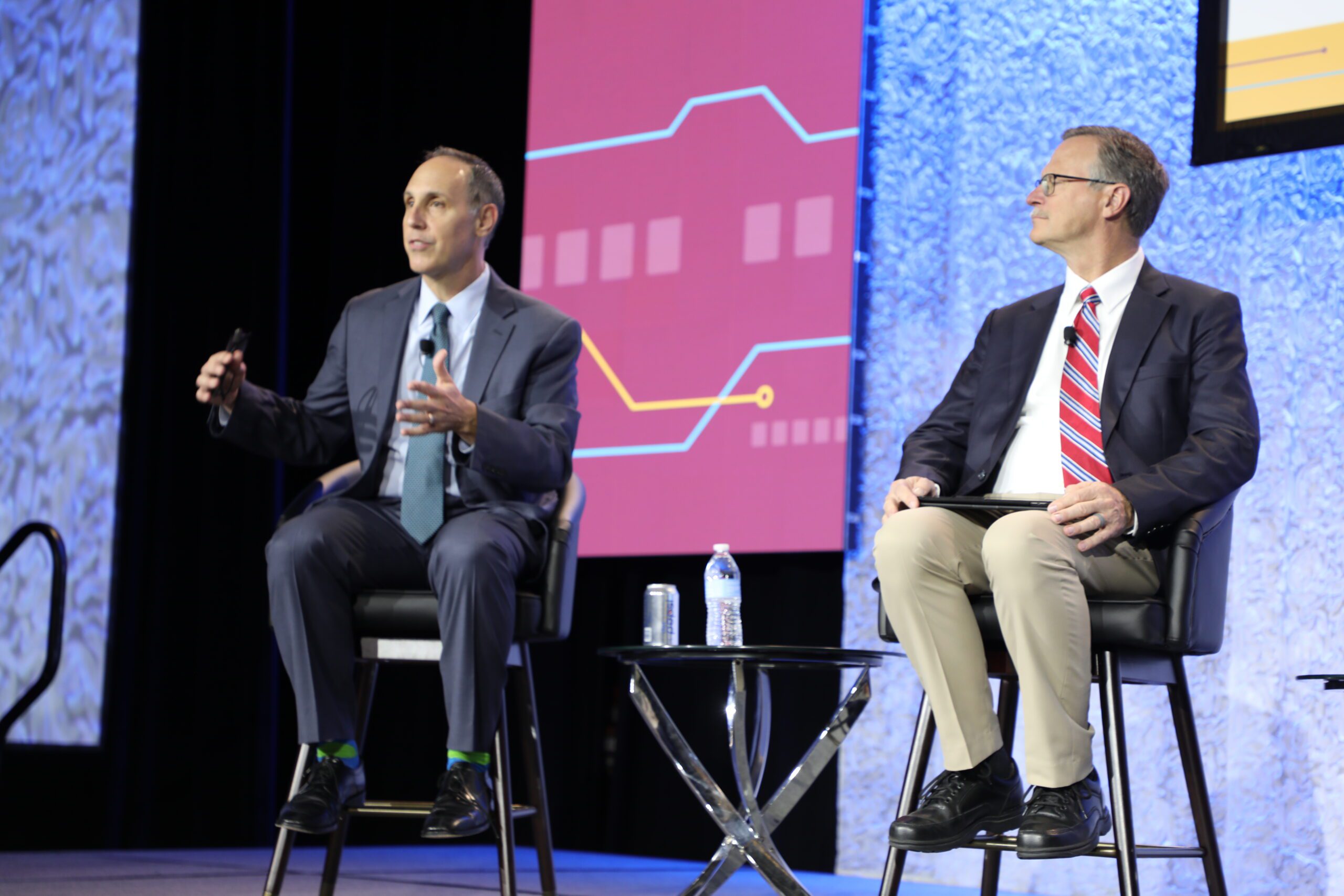 Two telecom leaders presenting on a large stage at a national conference. Larry Thompson and Mike Romano.